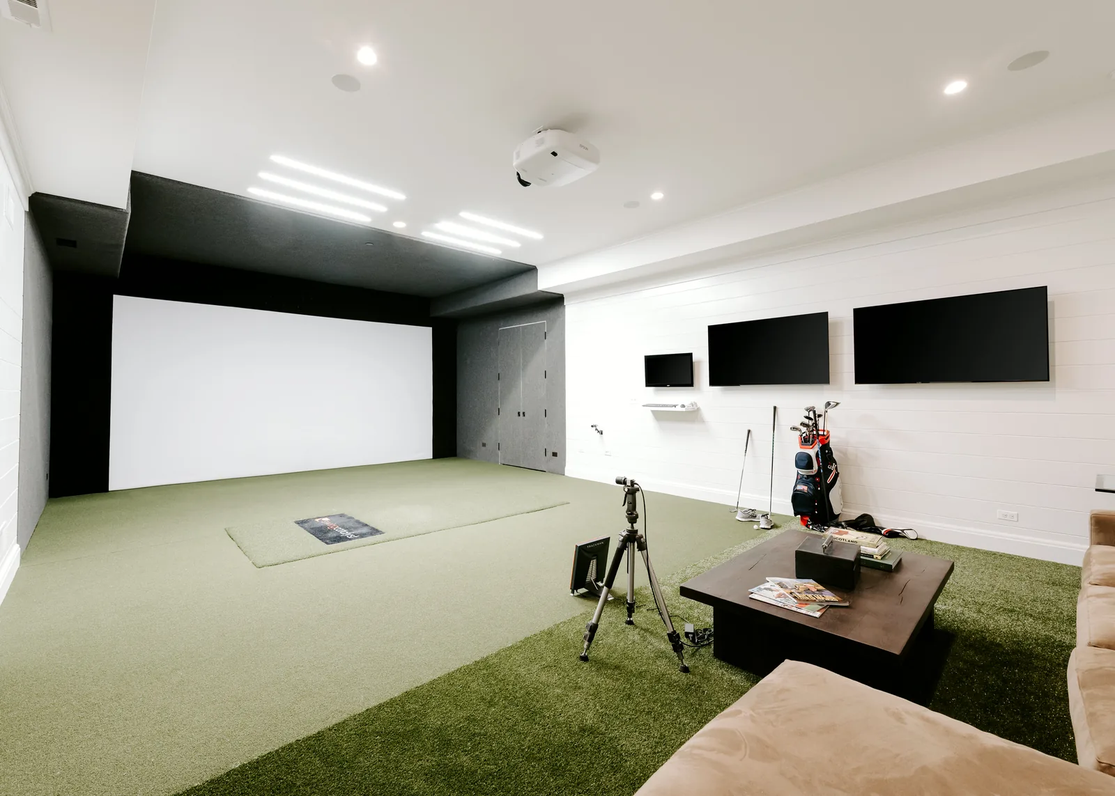 Retractable golf simulator integrated into a finished multi-purpose lounge