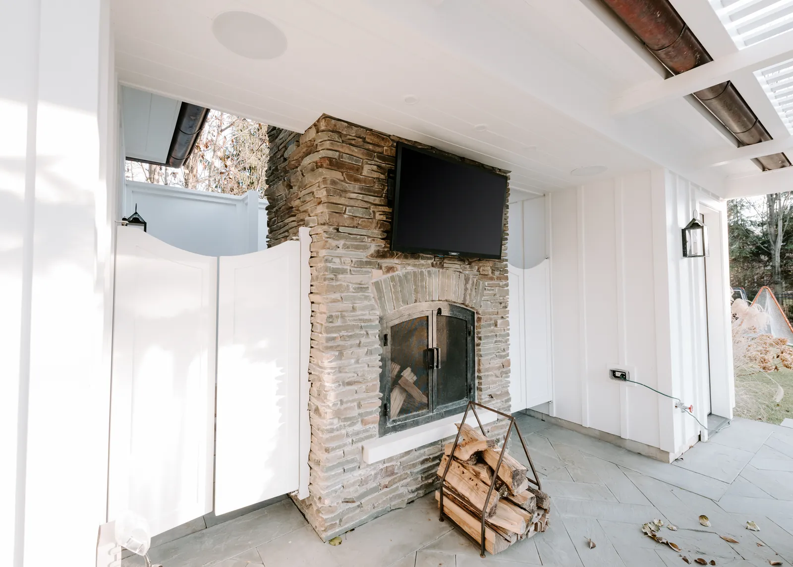 Vaulted great room with a wall-mounted television above a stone fireplace