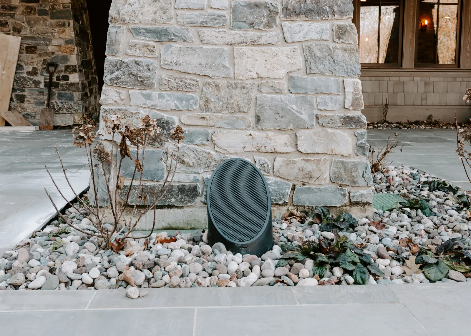 Discreet outdoor speaker installed beside a stone wall