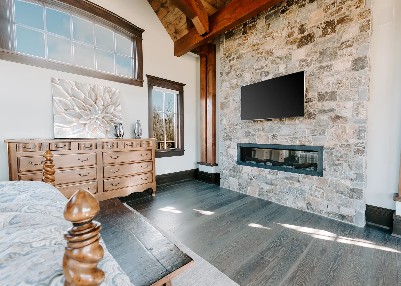 Bright great room with a wall-mounted television above a stone fireplace