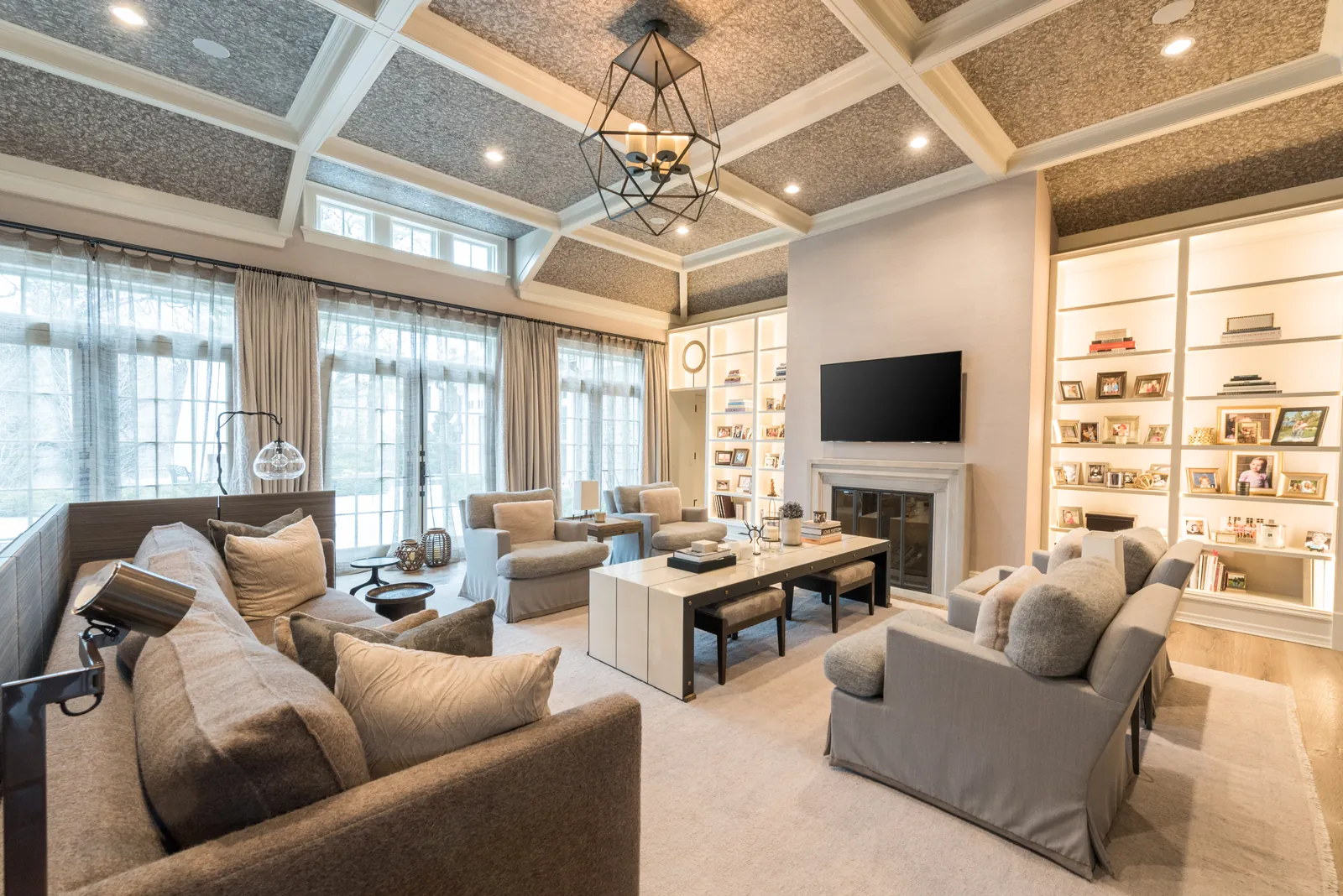Bright living room with a television above a stone fireplace and integrated built-in shelving